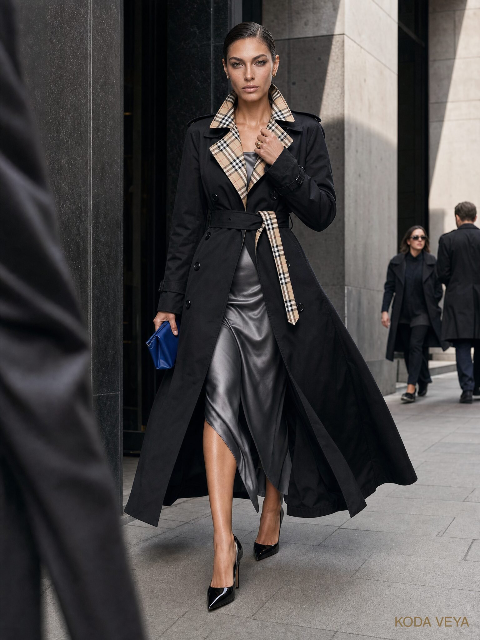 Black trench coat with heritage check lining worn over a metallic slip dress at night