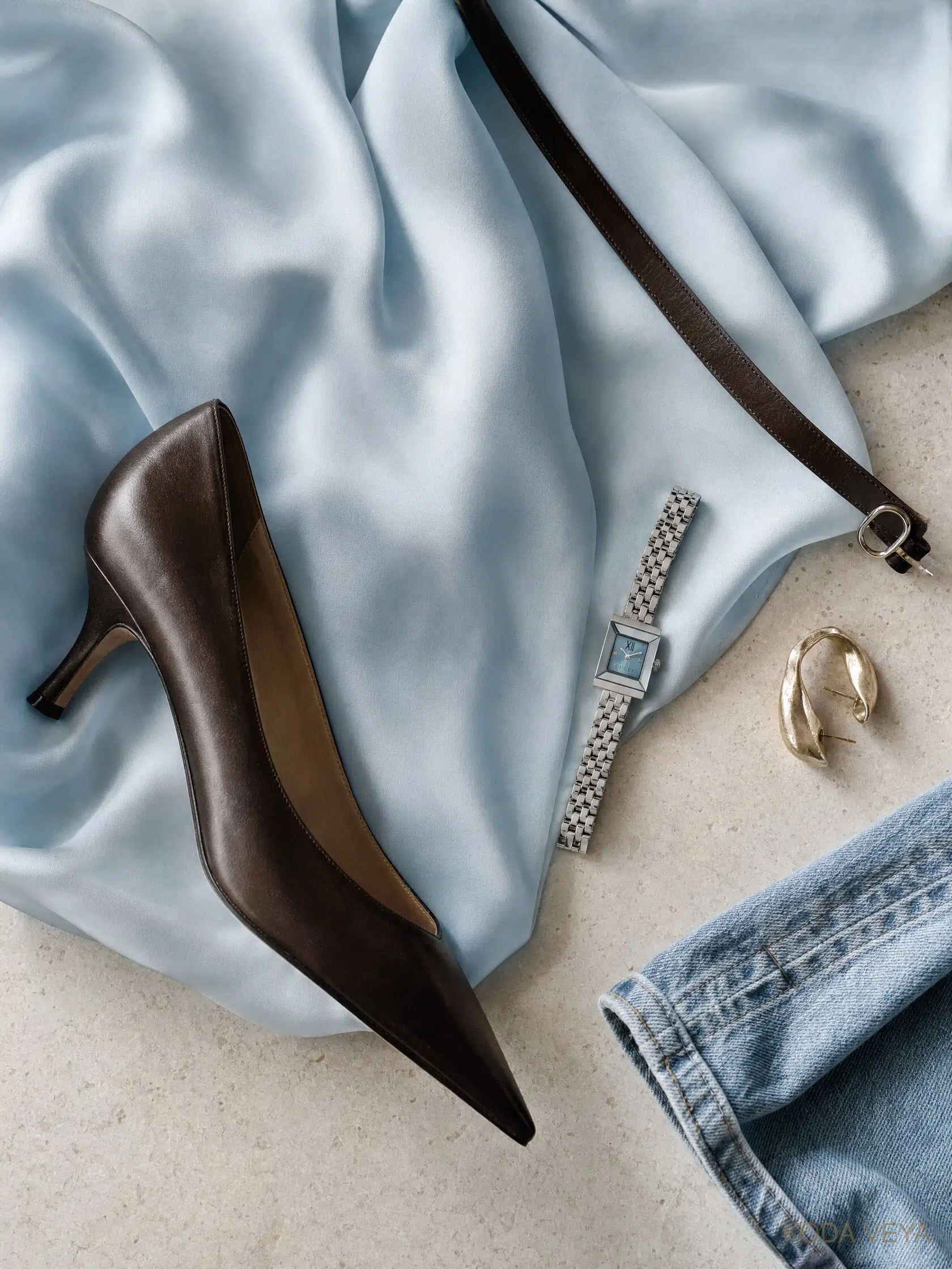 Colour Code 006, Ice Blue × Espresso lay-flat: ice-blue silk, an espresso leather kitten-heel pump, a slim espresso belt, a silver watch, gold earrings and washed denim