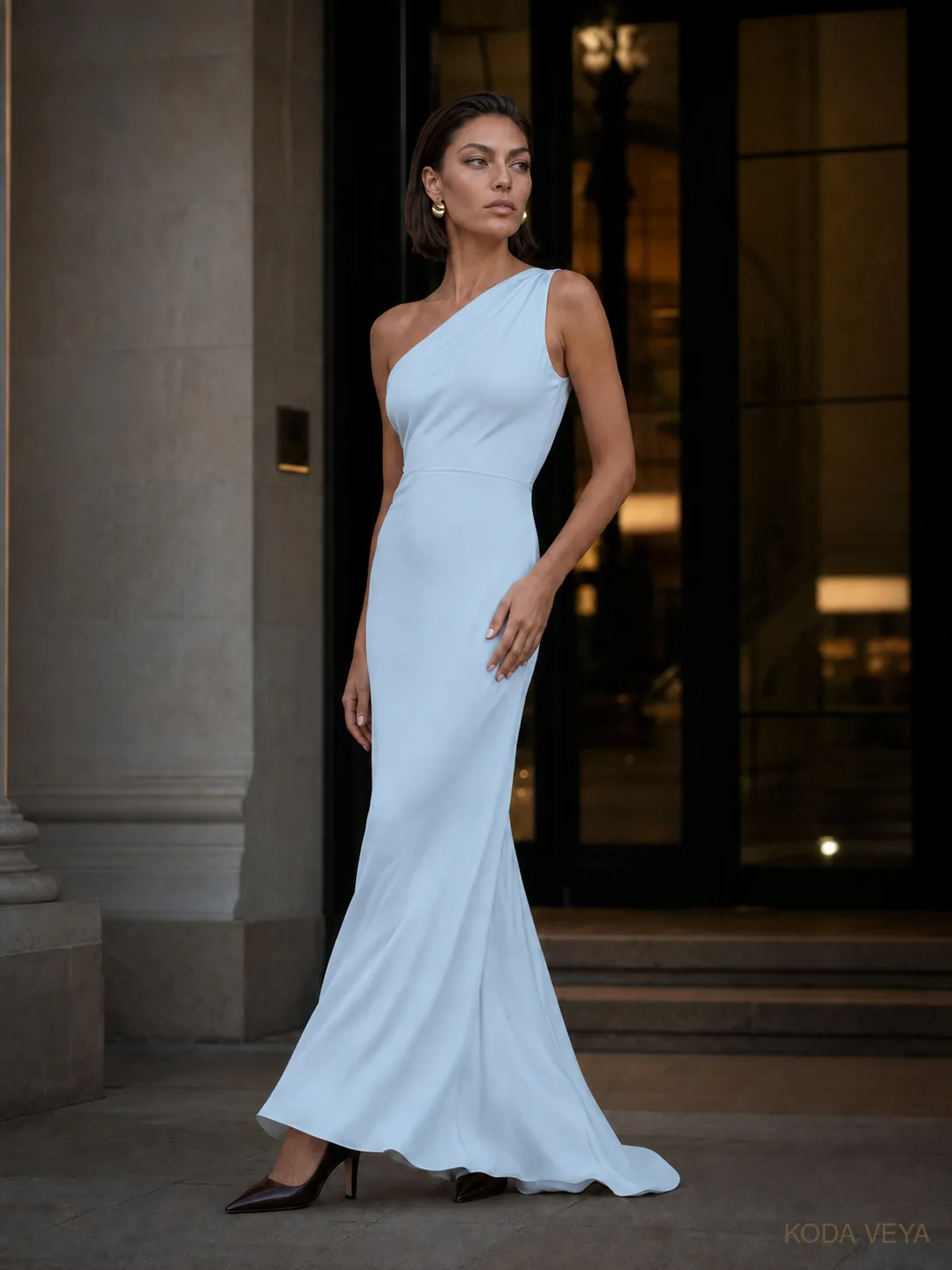 Colour Code 006, Ice Blue × Espresso, Look 04 Evening: Koda in a floor-length one-shoulder ice-blue satin dress with espresso pointed heels and gold earrings