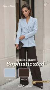 Woman in an ice-blue double-breasted blazer and espresso brown wide-leg trousers with pointed brown shoes and a brown clutch, standing outside a pale stone building