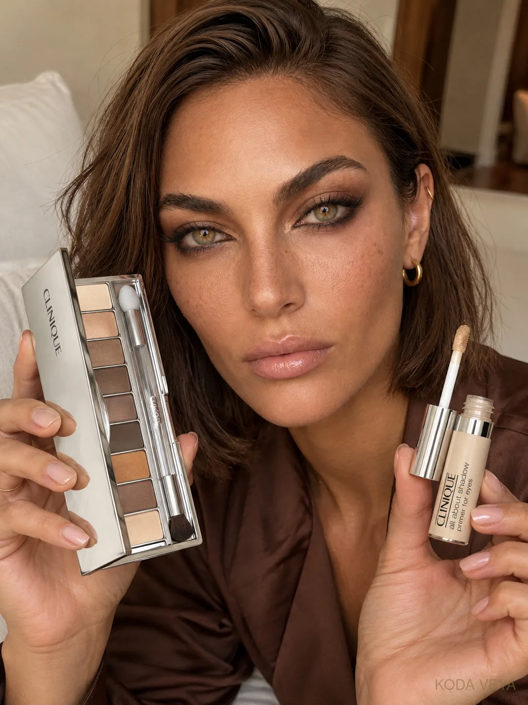 Koda with a warm smoky eye holding the Clinique All About Shadow palette in Nude Honey Mood and the All About Shadow eye primer